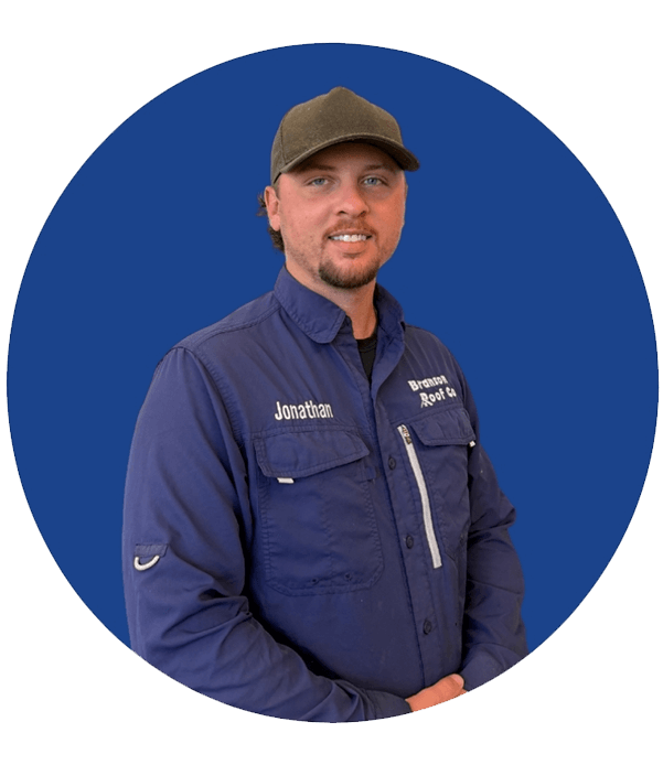 Jonathan, a crew member at Branson/Springfield Roof Co., dressed in company uniform and cap, smiling at the camera.
